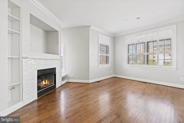a view of an empty room with wooden floor fireplace and a window