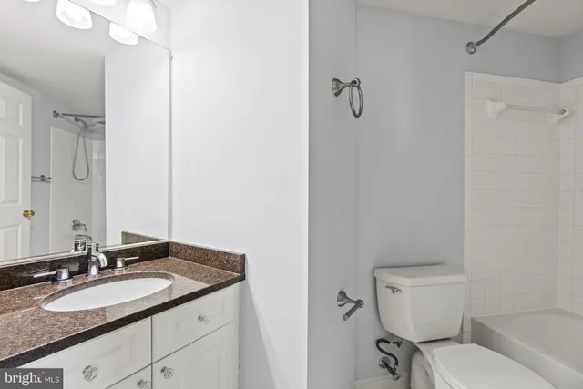 a bathroom with a granite countertop sink a toilet and a mirror