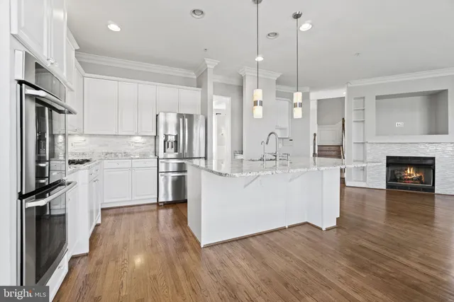 a kitchen with stainless steel appliances granite countertop a refrigerator a oven a stove and a wooden floors