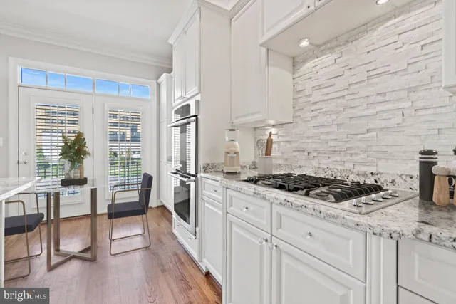 a kitchen with stainless steel appliances granite countertop a stove a sink and white cabinets