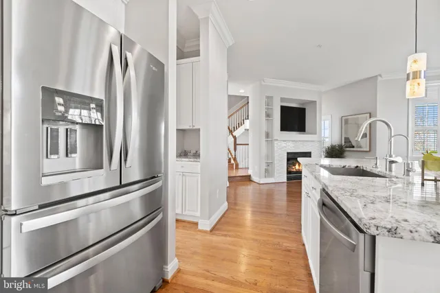 a kitchen with stainless steel appliances granite countertop a refrigerator a stove and a sink with wooden floor