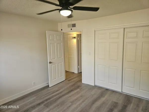 an empty room with wooden floor closet and windows