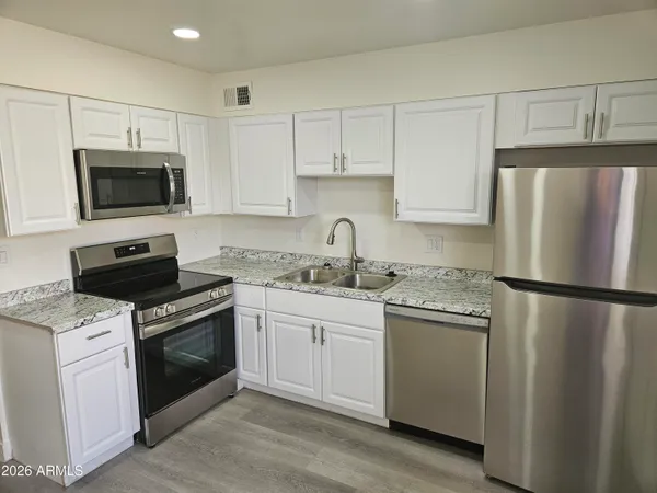 a kitchen with white cabinets and stainless steel appliances