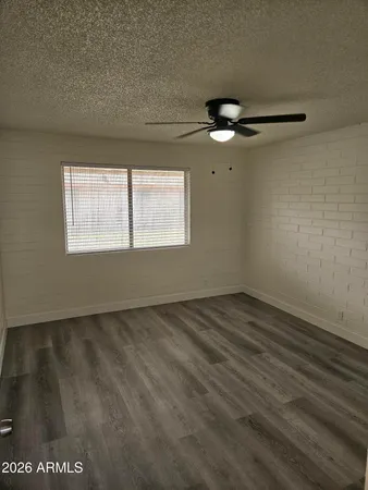 an empty room with wooden floor fan and windows