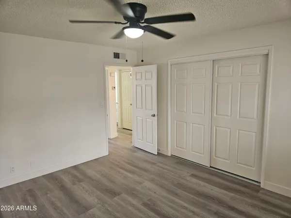 an empty room with wooden floor ceiling fan and windows