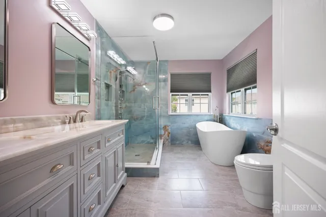 a spacious bathroom with a double vanity sink a toilet a mirror and a bathtub