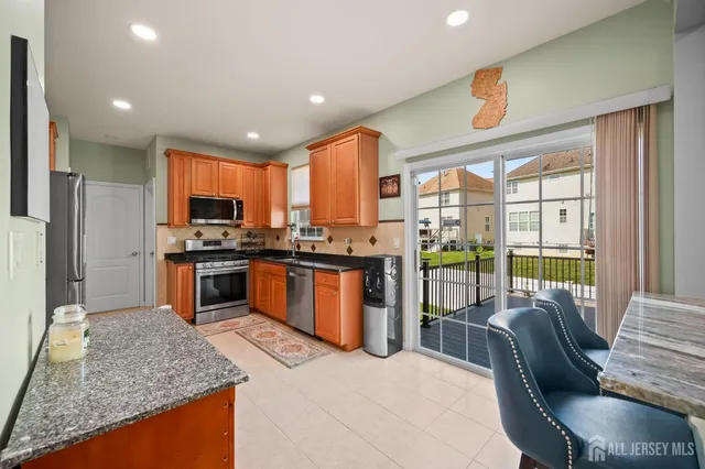 a kitchen with stainless steel appliances granite countertop sink stove refrigerator and cabinets