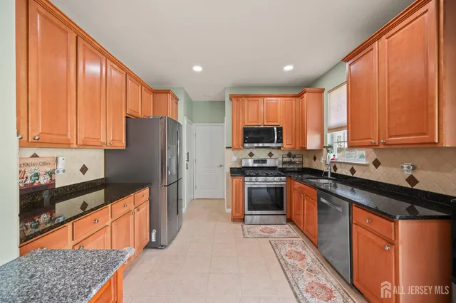 a kitchen with stainless steel appliances kitchen island granite countertop a stove a sink dishwasher a refrigerator and cabinets with wooden floor