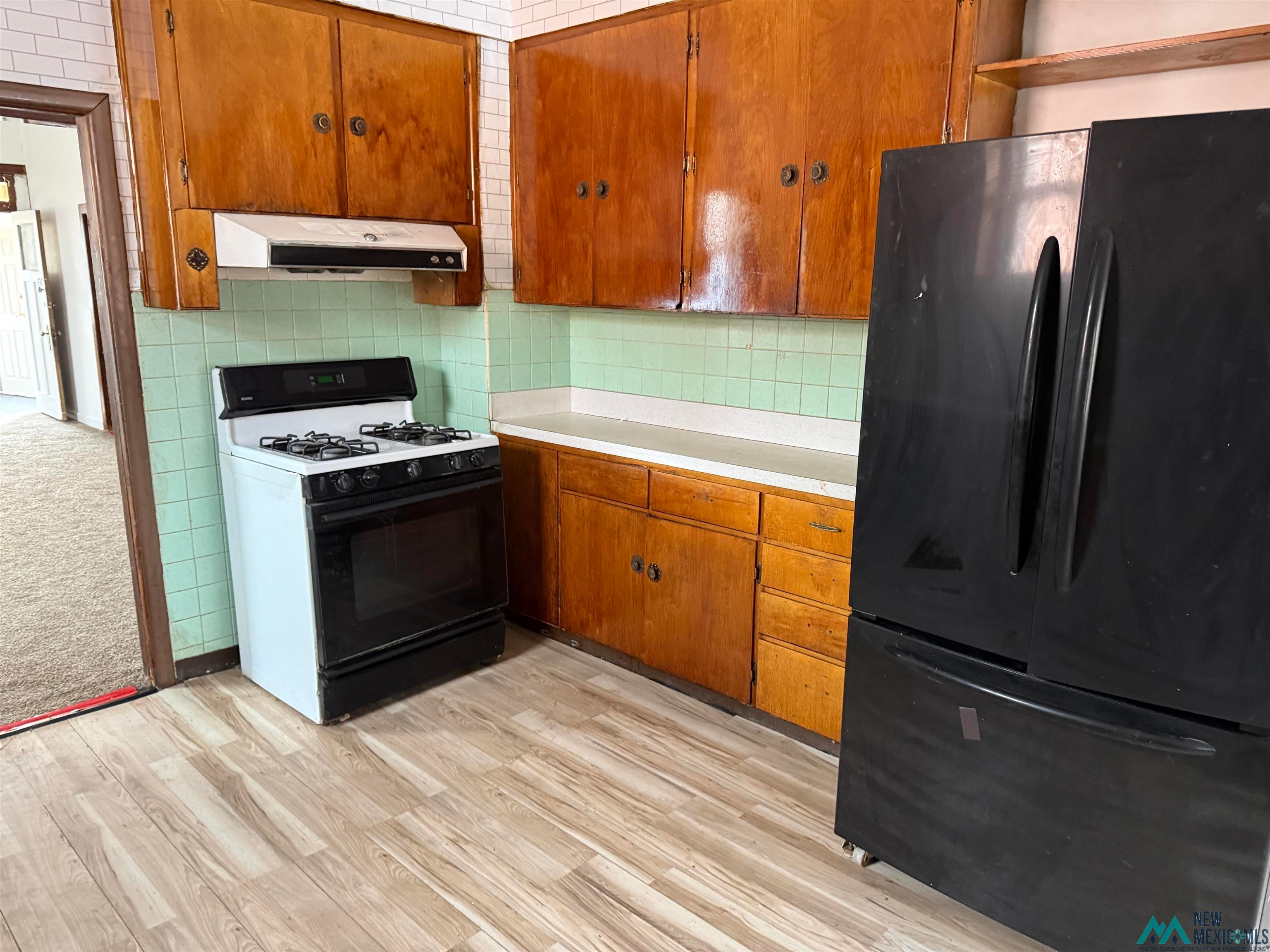524 South 1st Street Raton, NM 87740 - Photo 5 of 21 Kitchen featuring freestanding refrigerator, light countertops, gas stove, backsplash, and wood finish cabinets
