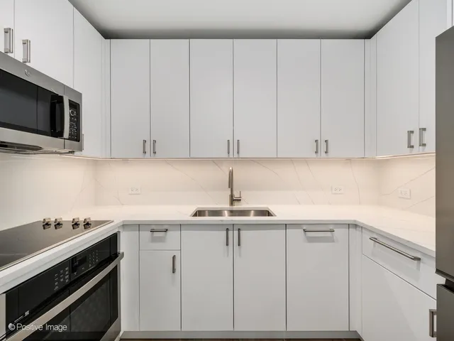 a kitchen with white cabinets stainless steel appliances and sink