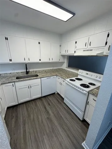 a kitchen with granite countertop a sink a stove and cabinets