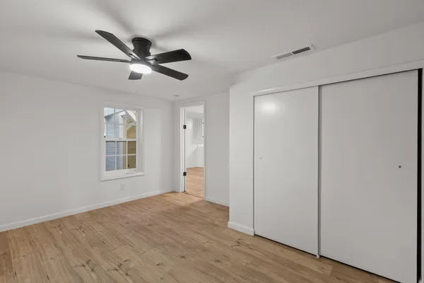 a view of empty room with wooden floor and fan