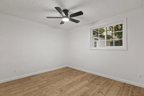 an empty room with wooden floor and ceiling fan