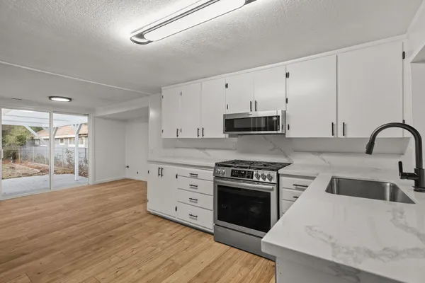 a kitchen with granite countertop a stove a sink and a microwave