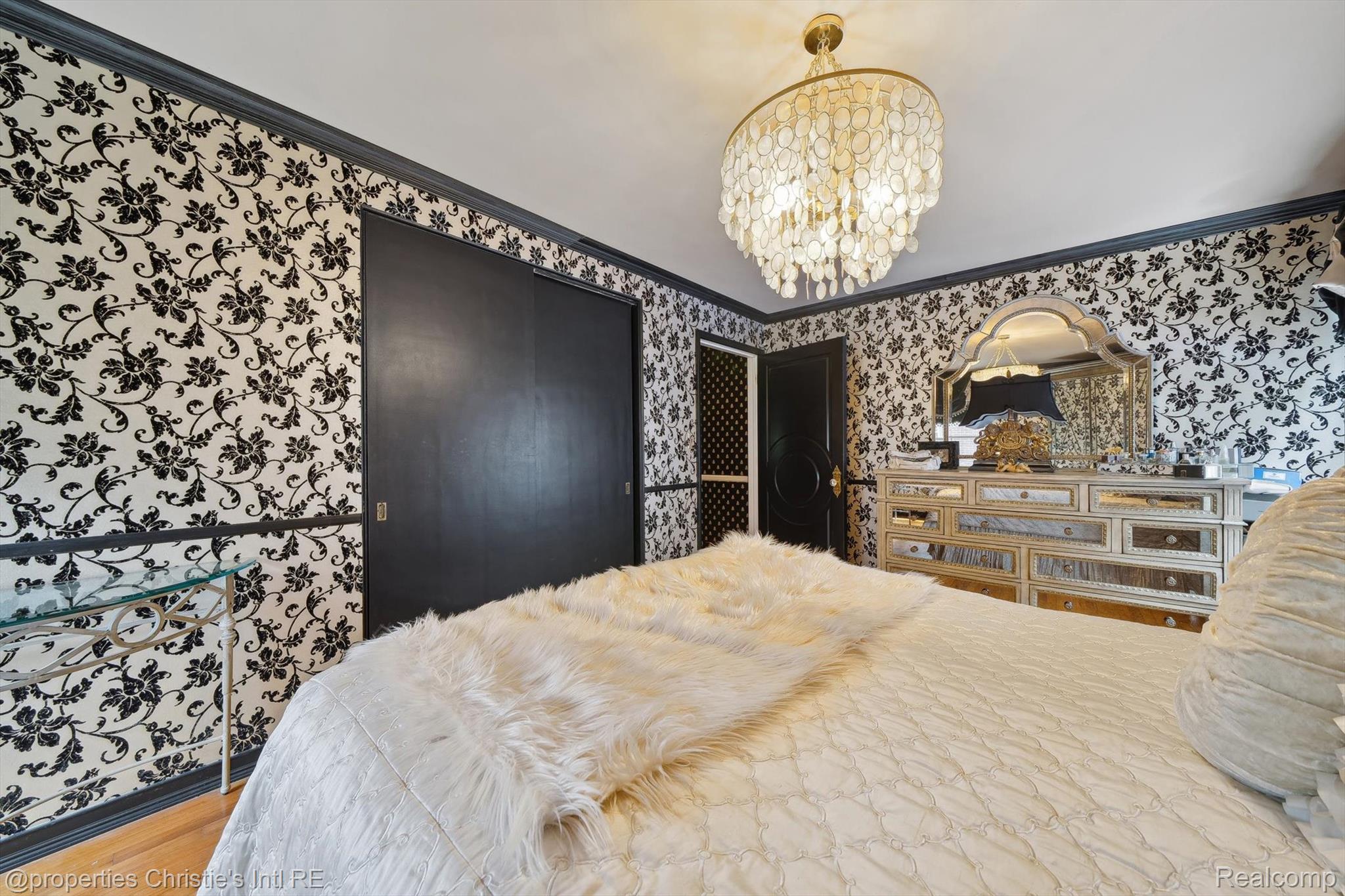 511 South Gulley Road Dearborn, MI 48124 - Photo 34 of 43 Black and white patterned wallpaper, dark crown molding, wood-finish flooring, black sliding closet doors, and an ornate chandelier