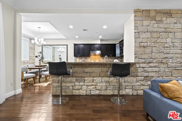 a kitchen with stainless steel appliances granite countertop a stove top oven a sink dishwasher a dining table and chairs with wooden floor