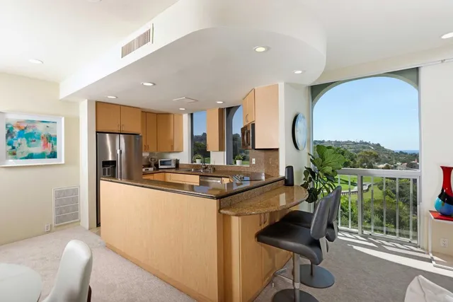 a kitchen with stainless steel appliances granite countertop a stove a refrigerator and a dining table with wooden floor