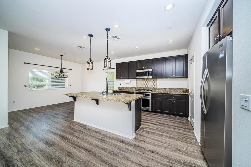 340 Falabella Lane Fallbrook, CA 92028 - Photo 16 of 63 a kitchen with stainless steel appliances kitchen island granite countertop a refrigerator a stove a sink and a wooden floors