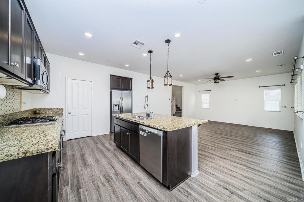 340 Falabella Lane Fallbrook, CA 92028 - Photo 18 of 63 a large kitchen with stainless steel appliances granite countertop a stove and a wooden floors