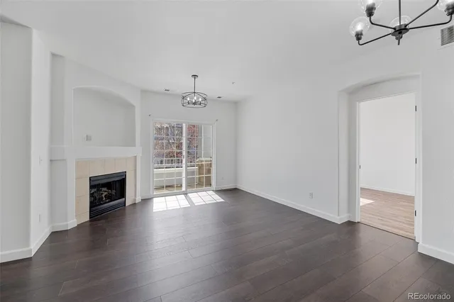 an empty room with wooden floor fireplace and windows