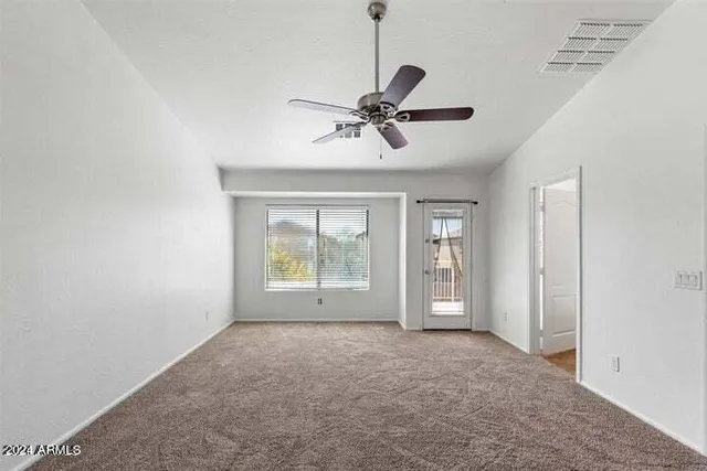 a view of an empty room with chandelier fan