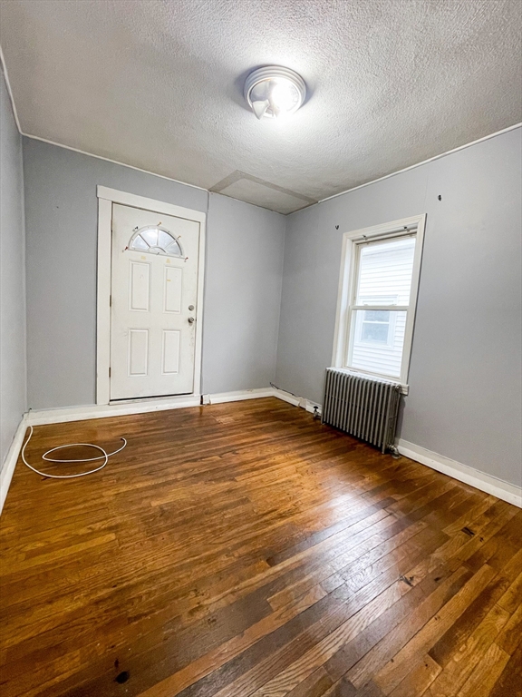 904 Main, Unit 1 Woburn, MA 01801 - Photo 2 of 5 a view of an empty room with wooden floor and a window