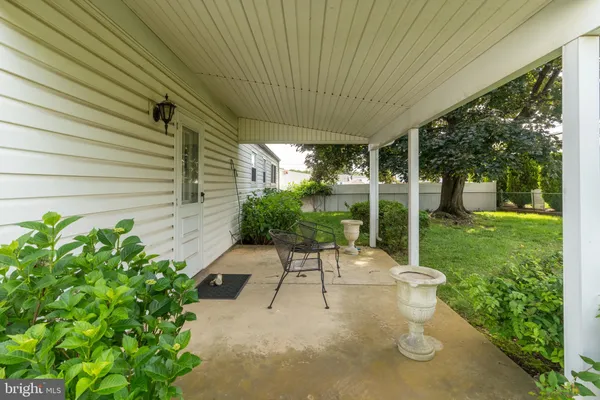 a view of a patio with table and chairs potted plants and floor to ceiling window