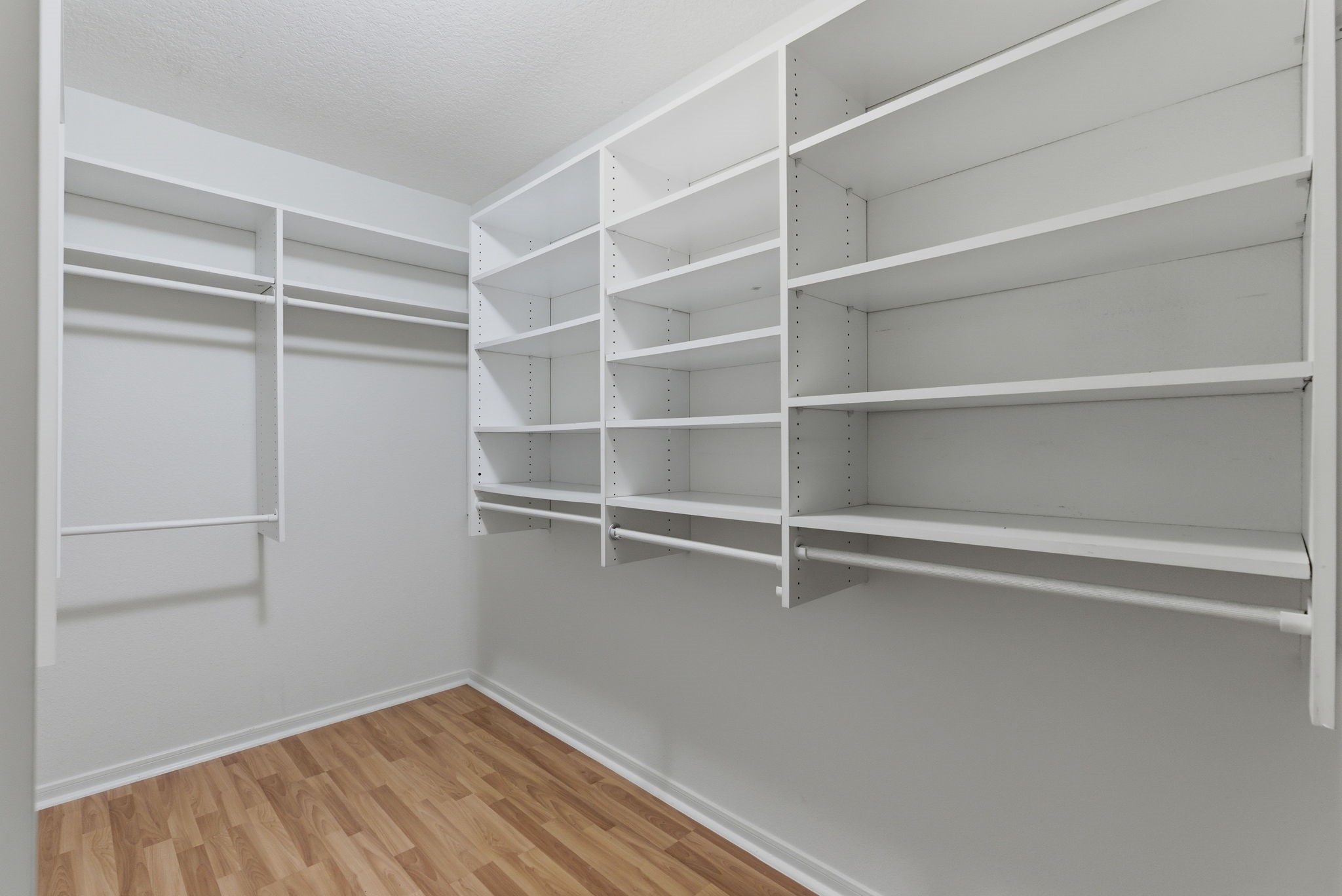 11 Dovewing Place Spring, TX 77382 - Photo 15 of 32 From the primary bedroom, a spacious walk-in closet with ample shelving and hanging space, featuring a light wood floor and a clean, white finish for a modern look.