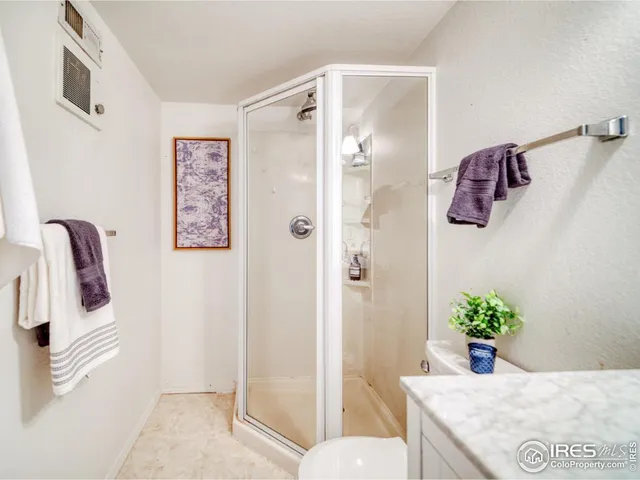 a bathroom with a granite countertop sink a mirror and shower