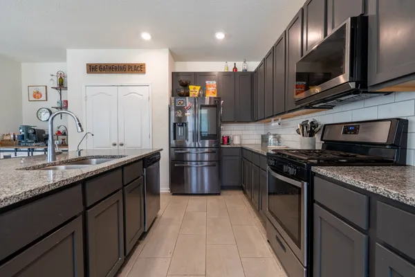 a kitchen with stainless steel appliances granite countertop a sink a stove top oven and refrigerator