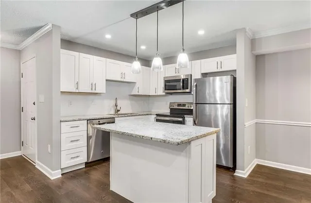 a kitchen with granite countertop white cabinets and black appliances