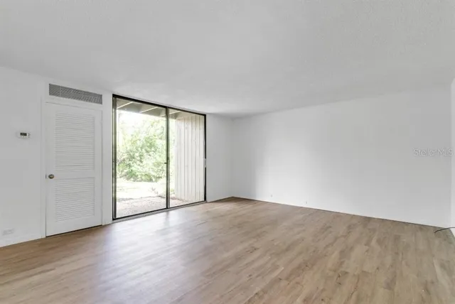 a view of an empty room with wooden floor and a window