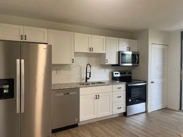 a kitchen with stainless steel appliances a refrigerator sink and microwave