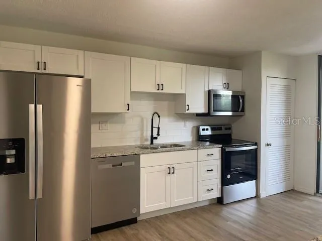 a kitchen with stainless steel appliances a refrigerator sink and microwave
