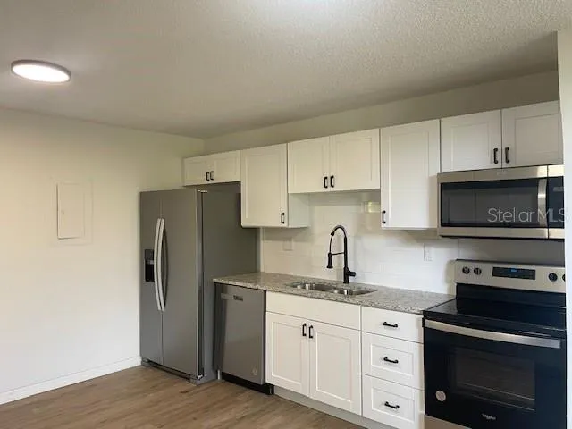 a kitchen with granite countertop a refrigerator stove and sink