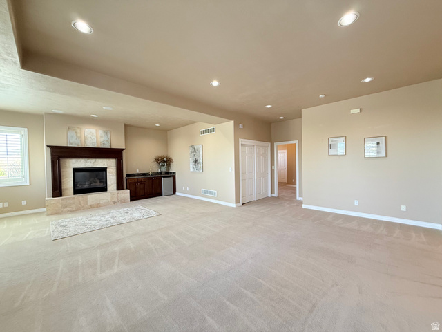 1562 Fairway Ridge Road Draper, UT 84020 - Photo 38 of 60 Spacious room featuring a fireplace with a wood mantle and stone surround, a built-in wet bar with cabinetry, recessed lighting, and neutral-toned carpeting