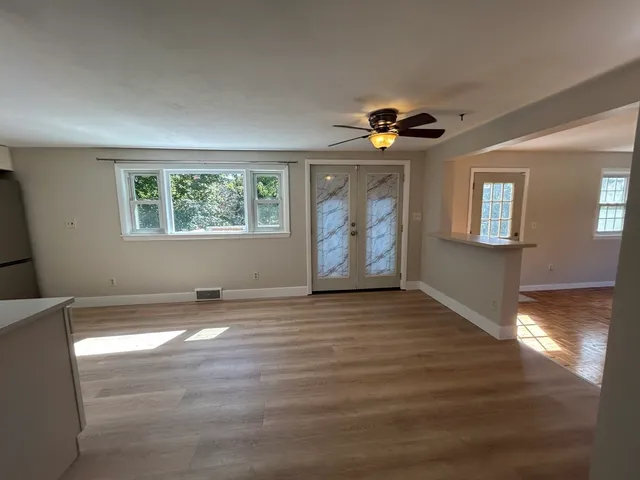 a view of an empty room with window and wooden floor