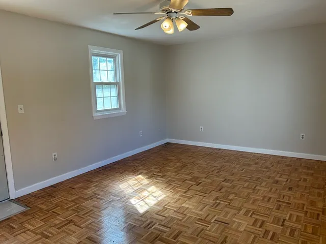 an empty room with wooden floor fan and windows