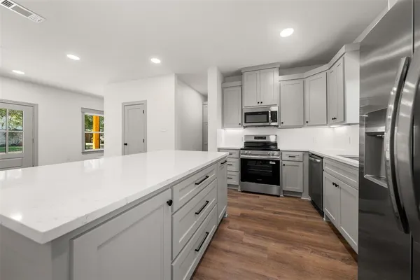a kitchen with white cabinets appliances and a window