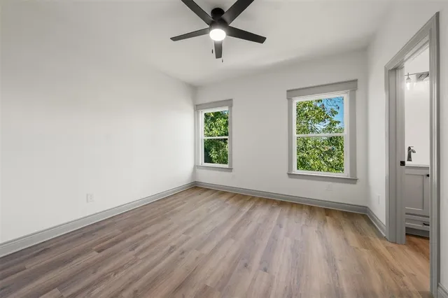 a view of an empty room with a window and wooden floor