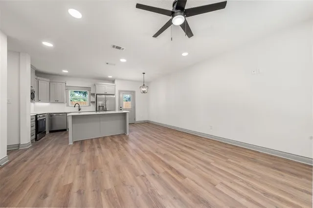 a view of a kitchen with a sink and dishwasher a refrigerator with wooden floor