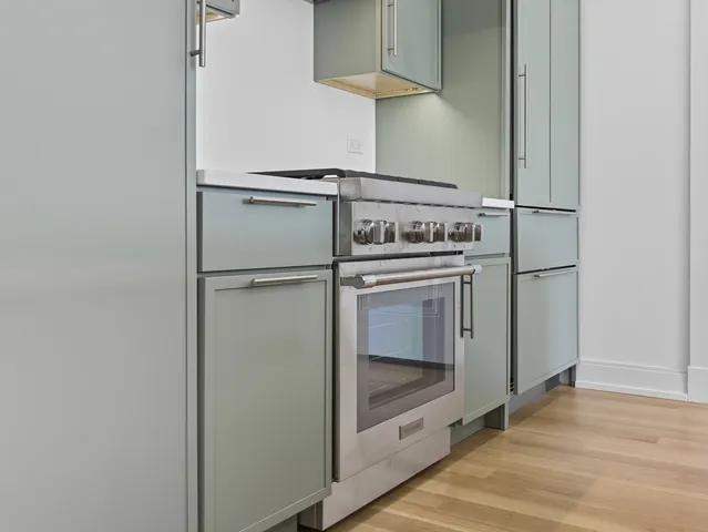 a view of a kitchen with stainless steel appliances wooden floor and cabinets