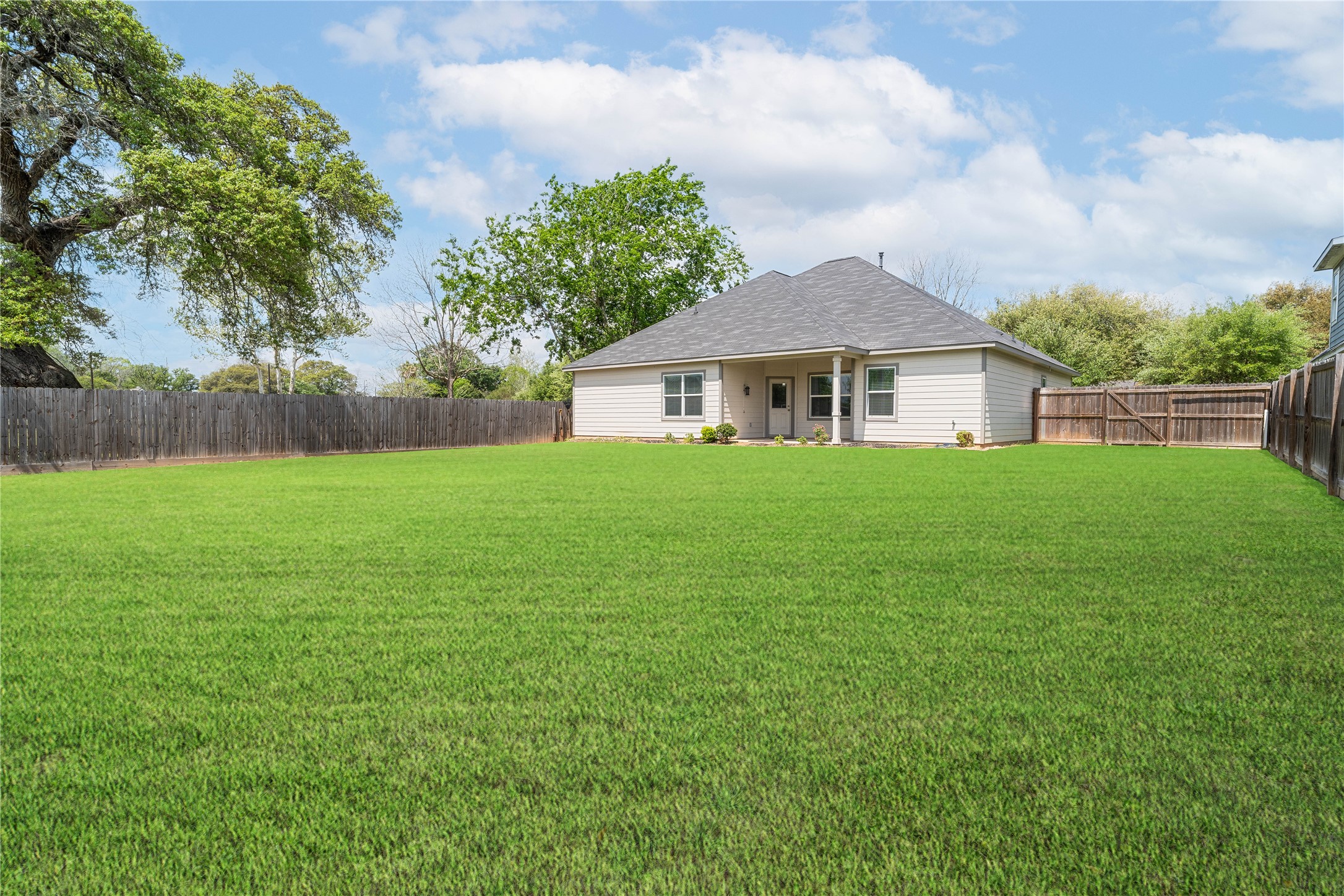 231 McCormick Street Columbus, TX 78934 - Photo 25 of 27 Backyard – Expansive, fully fenced backyard offering a large grassy area perfect for outdoor activities, pets, or future enhancements.