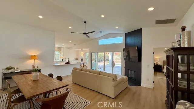 a living room with furniture and a dining table with wooden floor