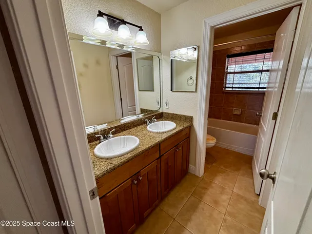 a bathroom with a double vanity sink a toilet and a mirror