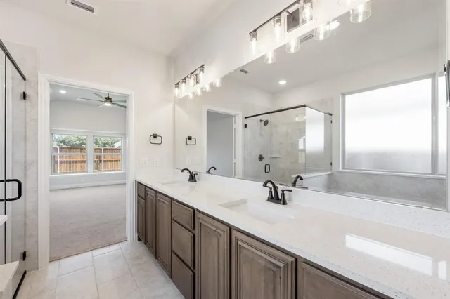 a bathroom with double vanity sinks a vanity a lamp and a mirror