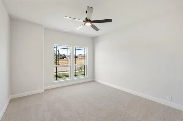 an empty room with windows and ceiling fan