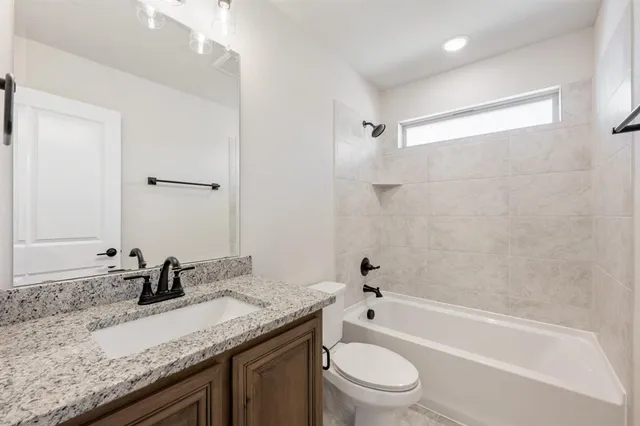 a bathroom with a granite countertop sink a toilet and bathtub