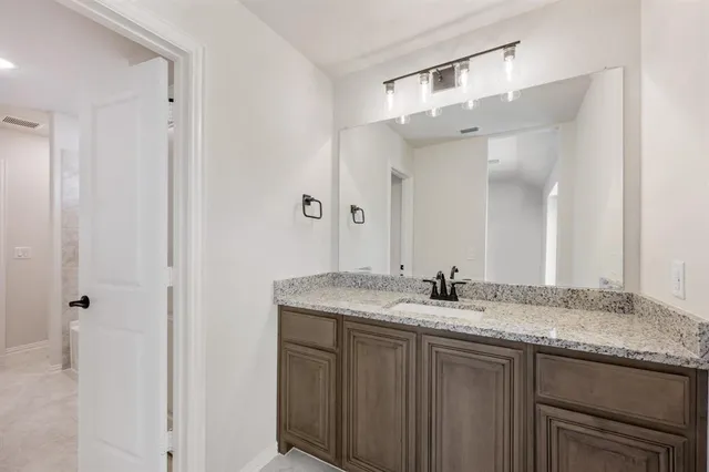 a bathroom with a granite countertop sink and a mirror