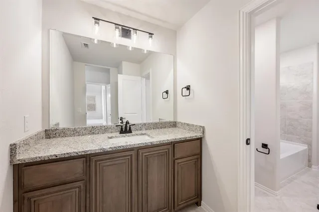 a bathroom with a granite countertop sink and a mirror